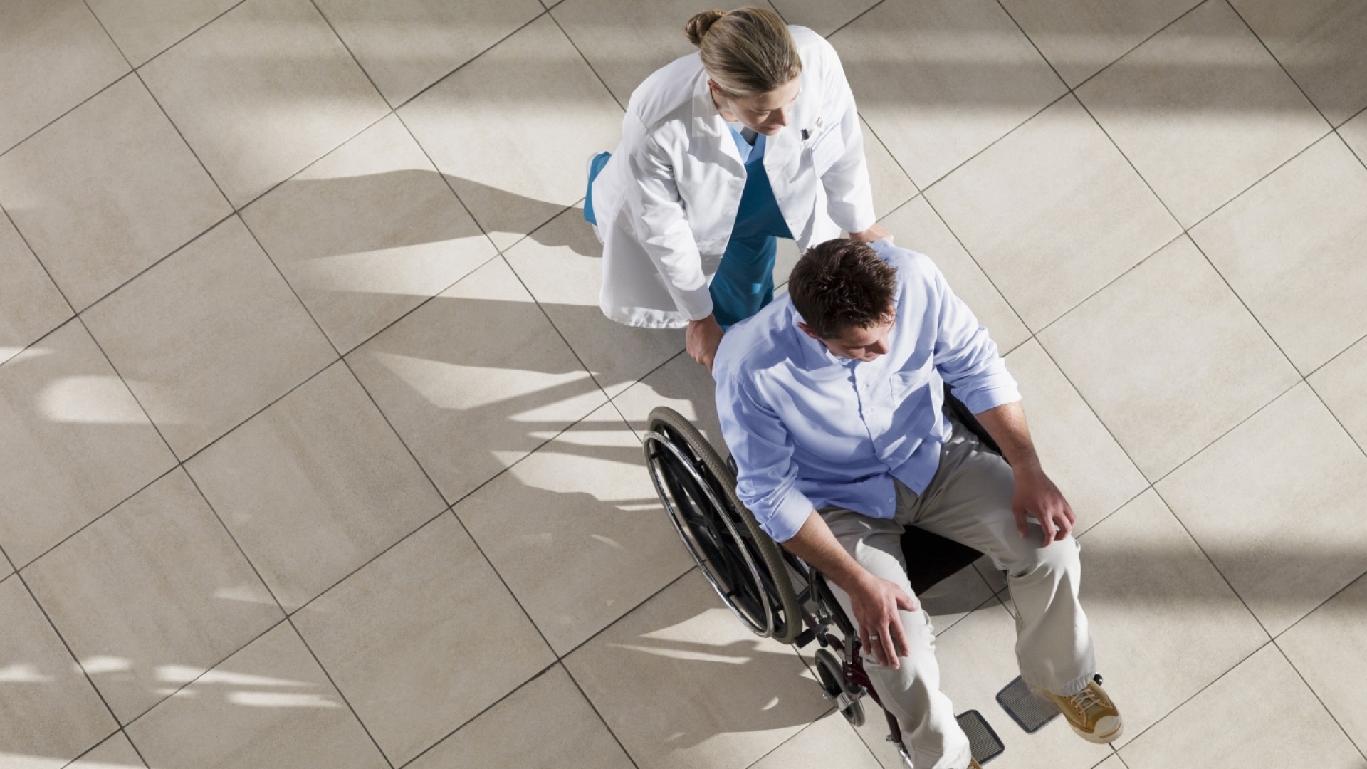 Ärztin schiebt Patient im Rollstuhl