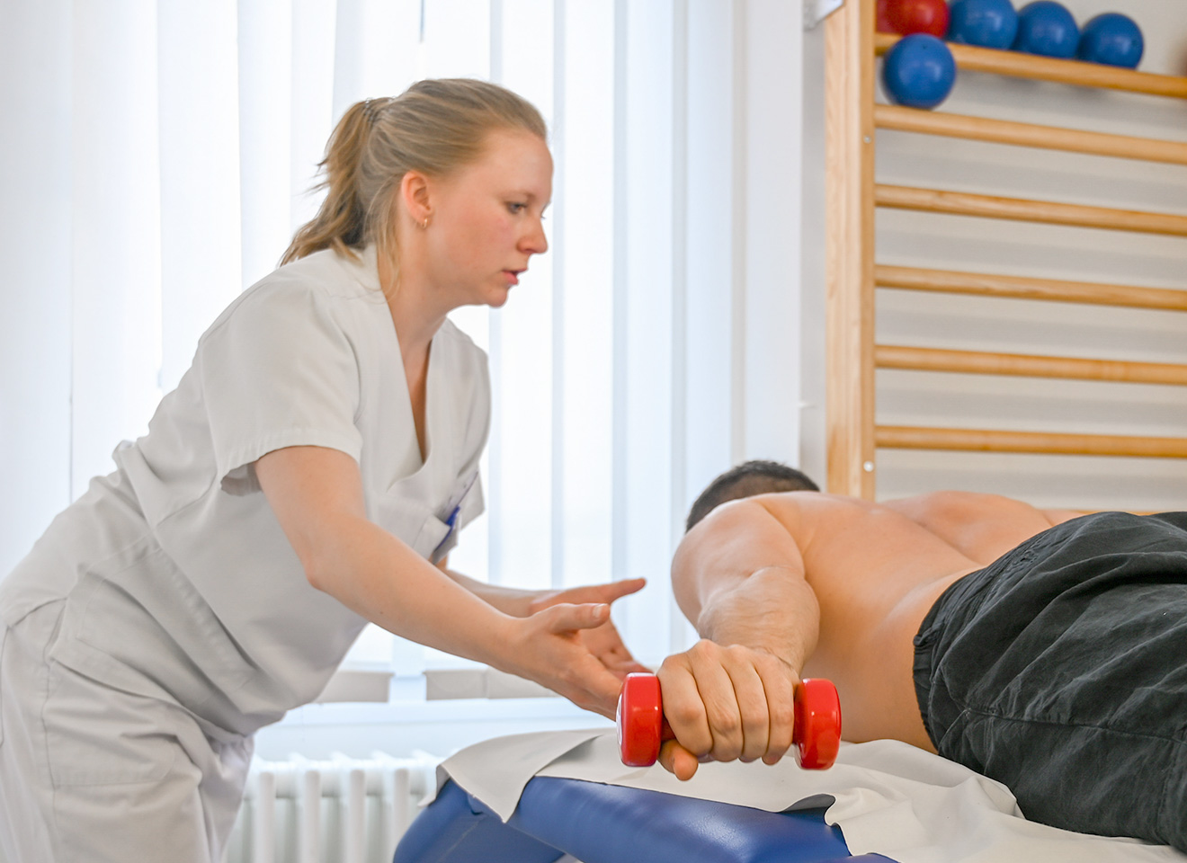 Physiotherapeutin behandelt den Arm eines Patienten