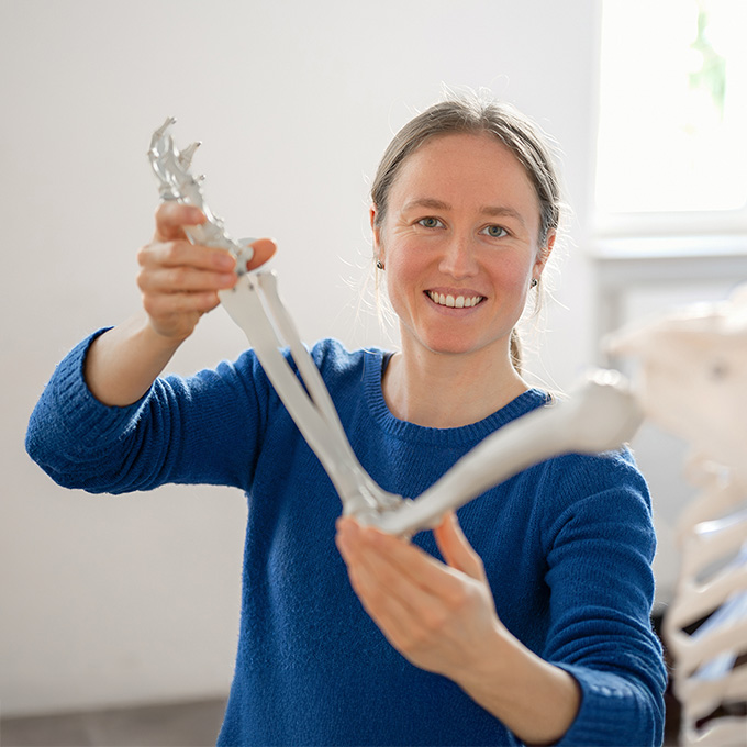 Physiotherapeutin hält den Arm eines Skeletts in der Hand