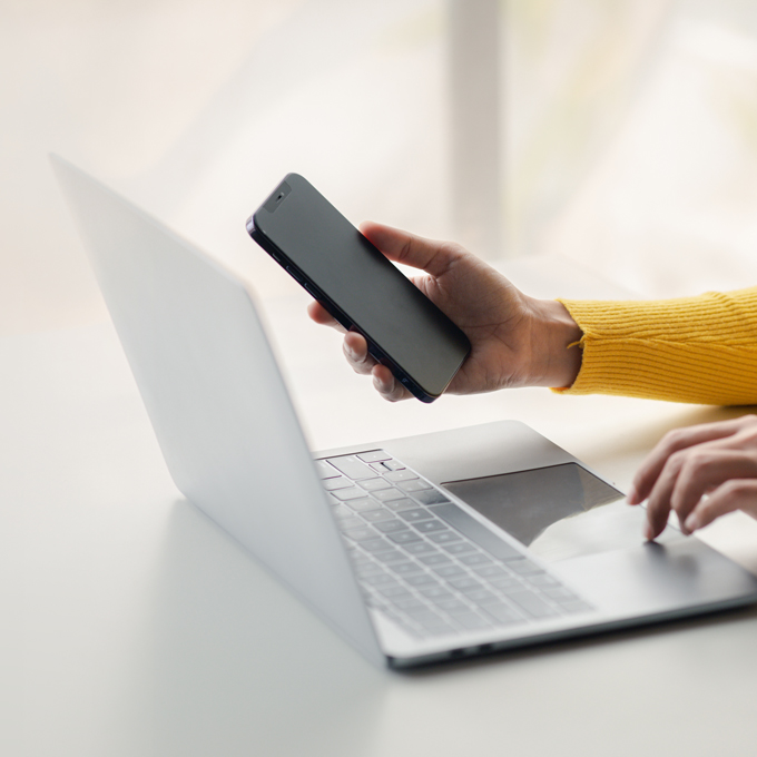 Hände, die einen Laptop und ein Handy verwenden