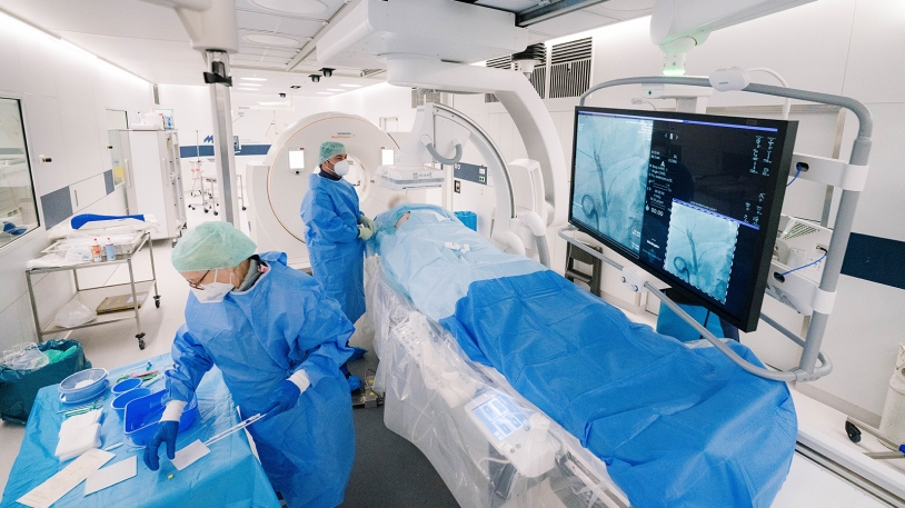 Prof. Philipp M. Paprottka, Chefarzt der Sektion Interventionelle Radiologie am Universitätsklinikum rechts der Isar, bei der Behandlung eines Patienten mit dem neuen Angio/CT-Hybridsystem. Foto: Siemens Healthineers