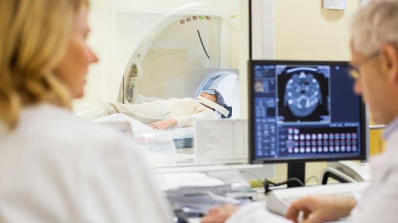Ärztin und Arzt an einem Bildschirm eines Magnetresonanztomographie-Geräts sitzend Ärztin und Arzt an einem Bildschirm eines Magnetresonanztomographie-Geräts sitzend
